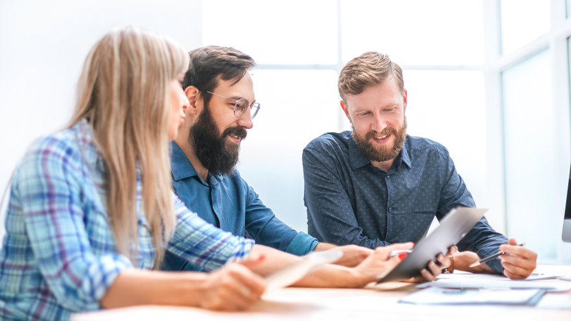 drei Kollegen gucken zusammen auf einen Tablet drei Kollegen gucken zusammen auf einen Tablet